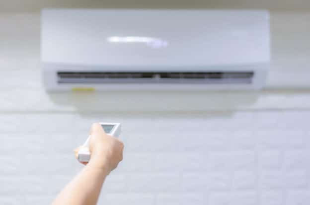 A hand with a remote control turning on the AC.