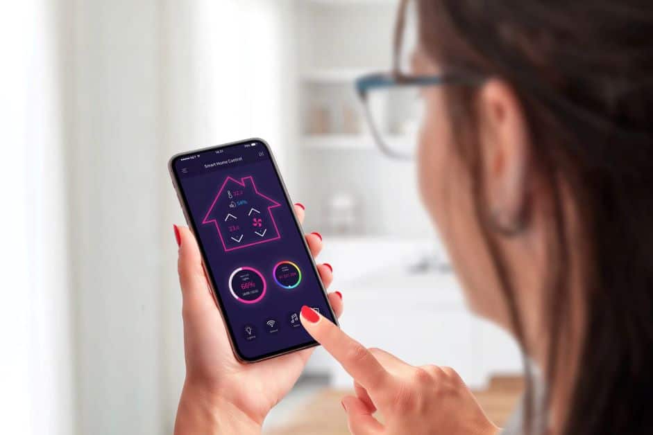 A young woman controls a smart thermostat by using a phone app.