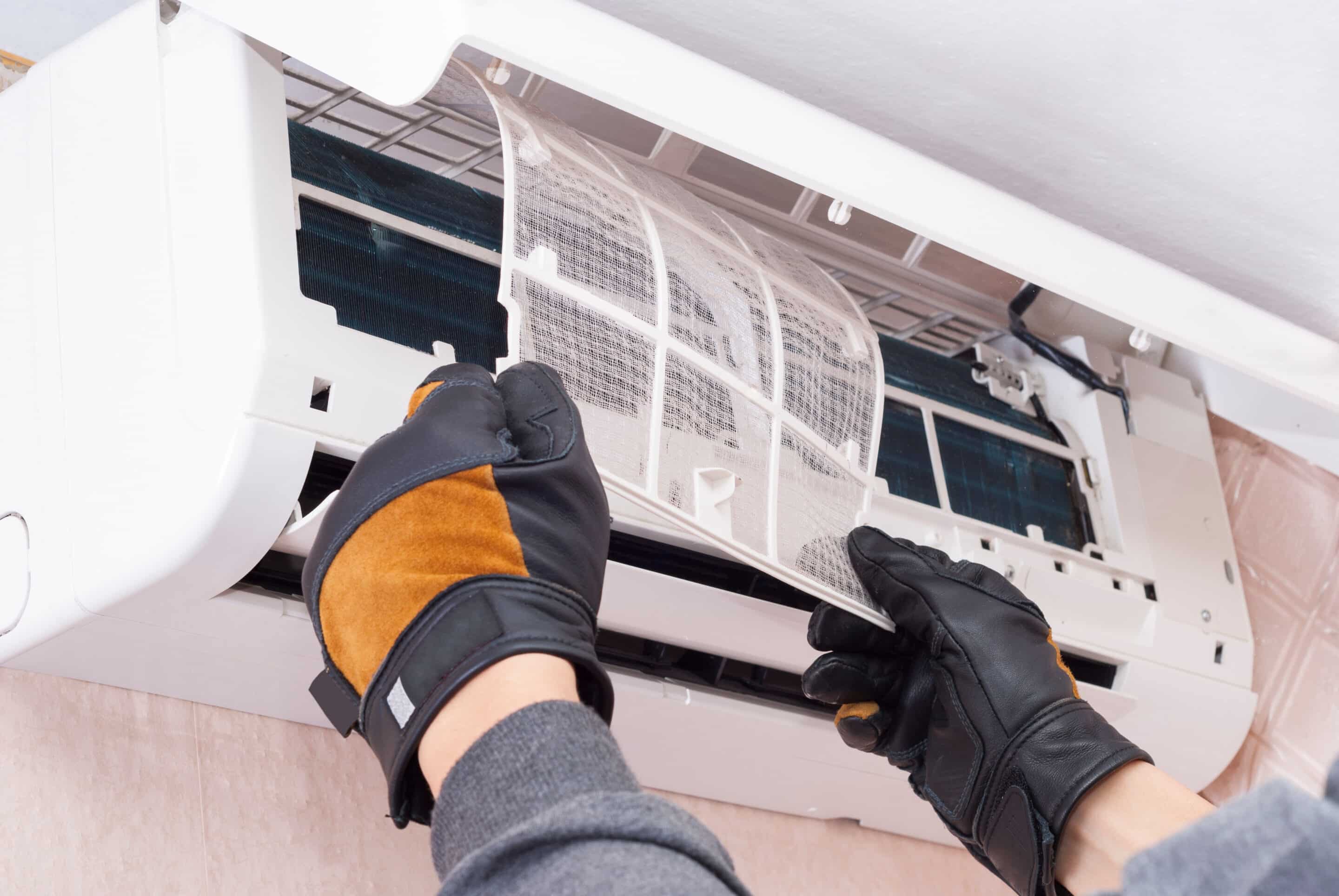 A professional cleans and repairs an air conditioner.