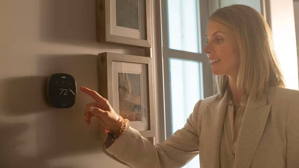 a woman sets her programmable thermostat and wireless thermostat before leaving home